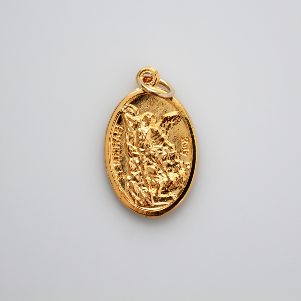 Gold tone Archangel Michael double-sided oval medal. The front depicts St. Michael and the reverse depicts a guardian angel