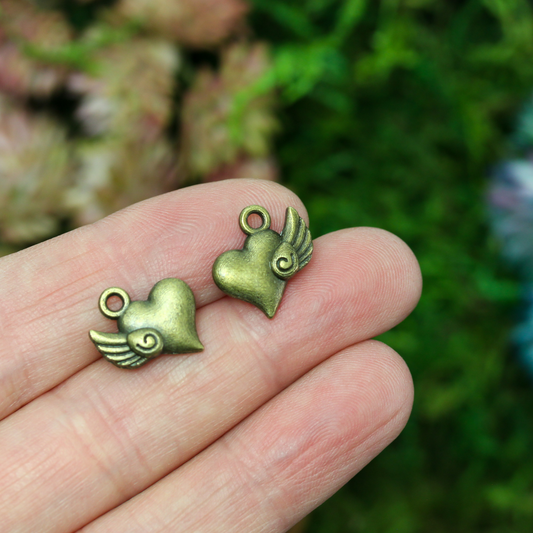 Heart charm with a small wing on the side in antiqued bronze color, 13mm x 13mm