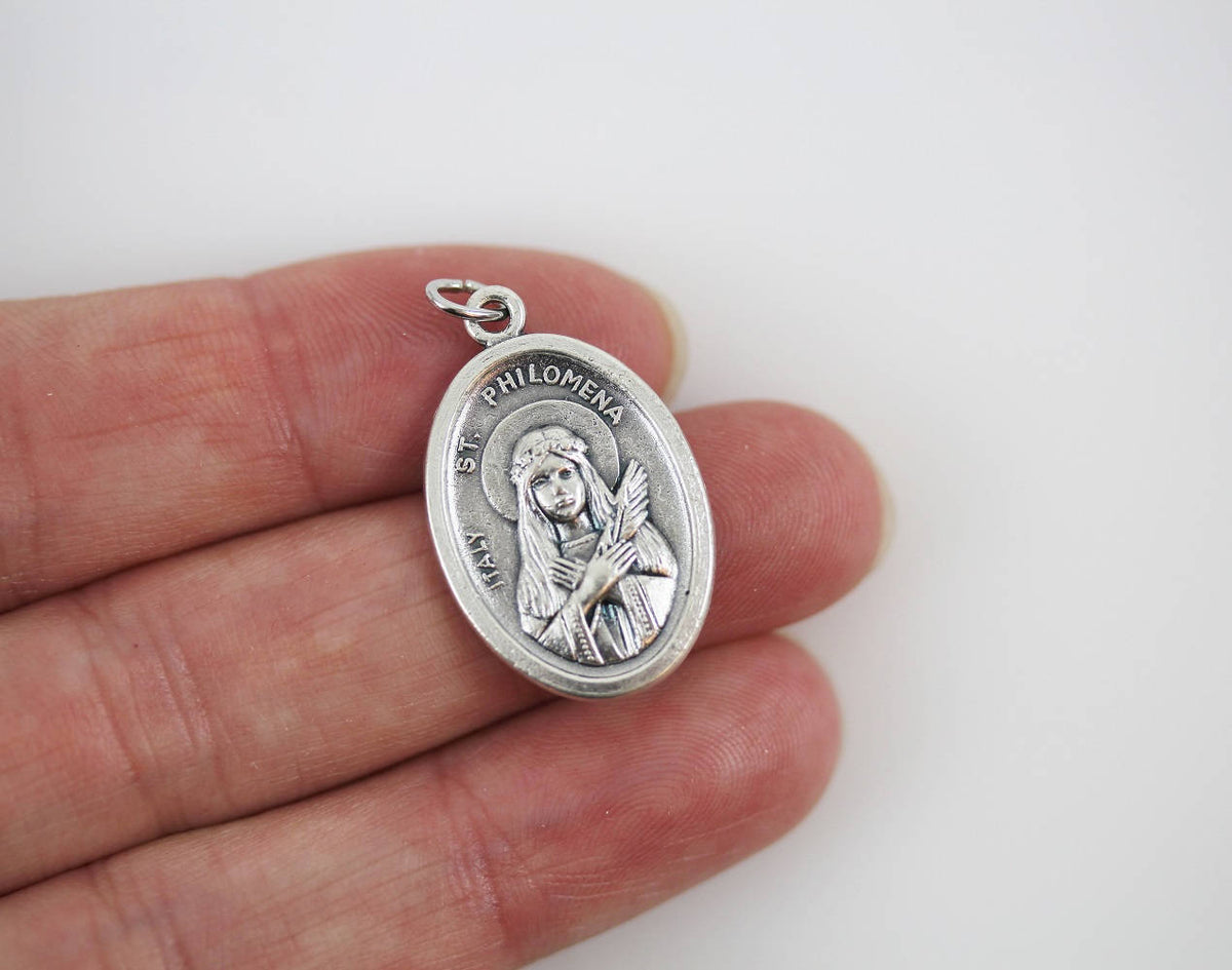 womans hand holding catholic patron saint medal