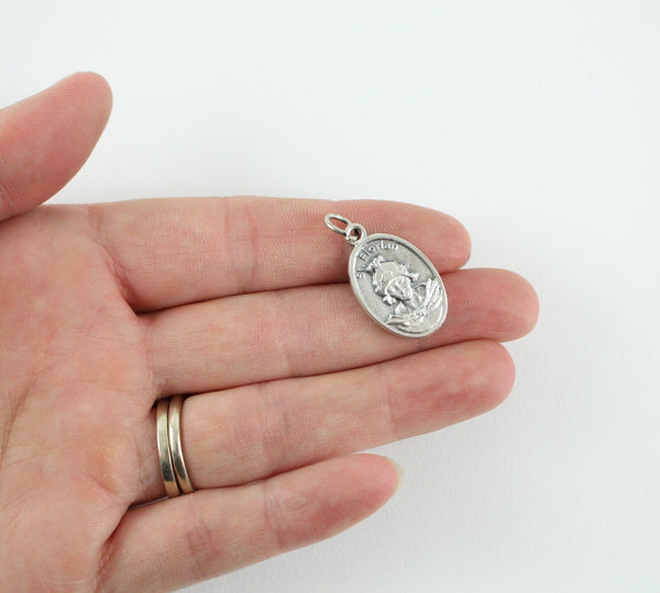womans hand holding one inch oval patron saint medal