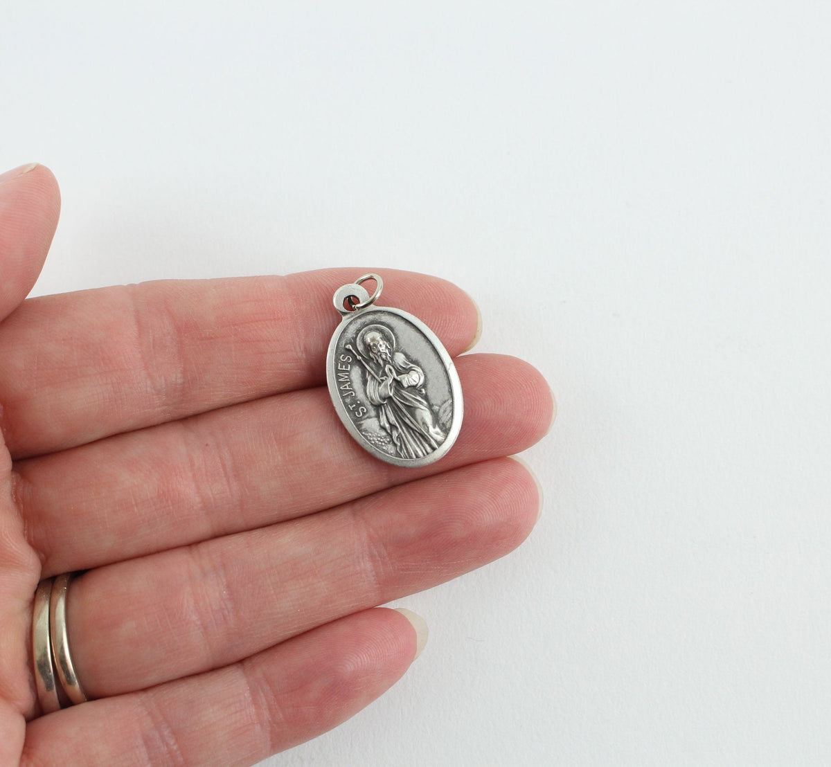 womans hand holding catholic patron saint medal