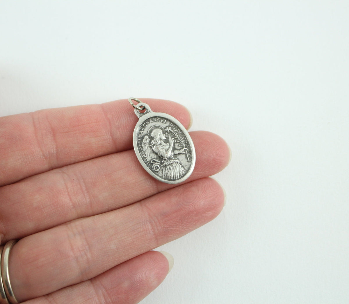 womans hand holding catholic patron saint medal