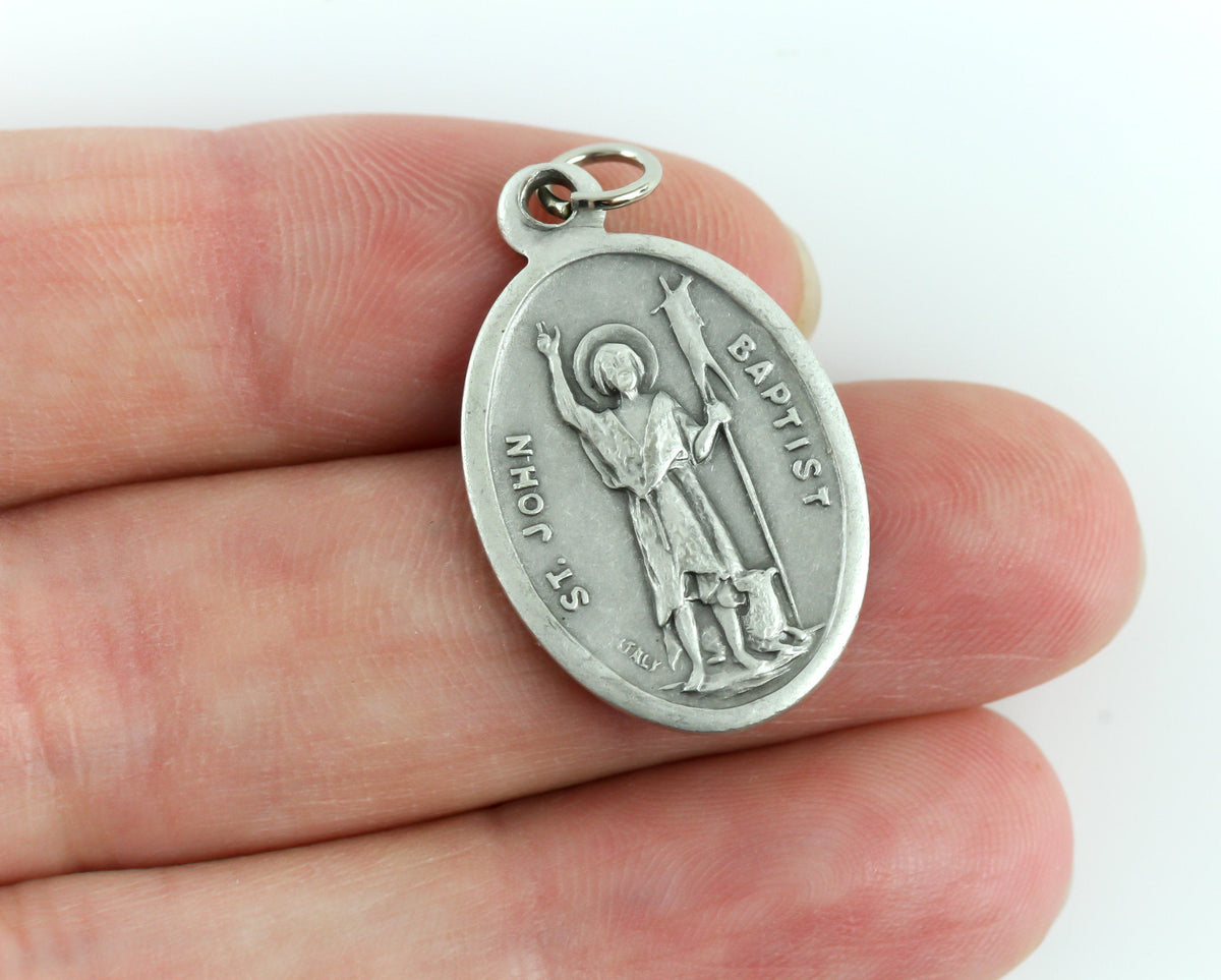 womans hand holding catholic patron saint medal
