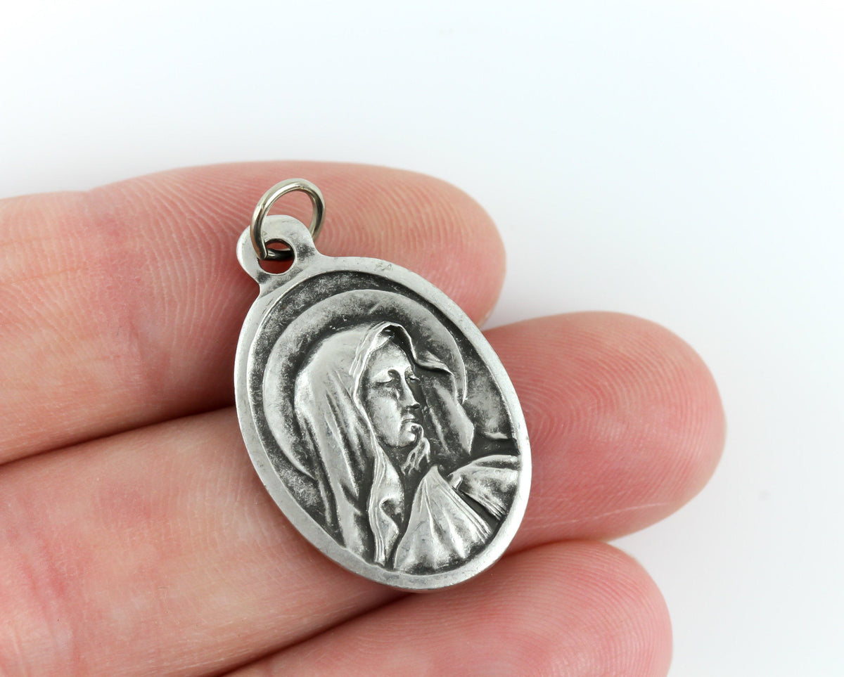 womans hand holding catholic patron saint medal
