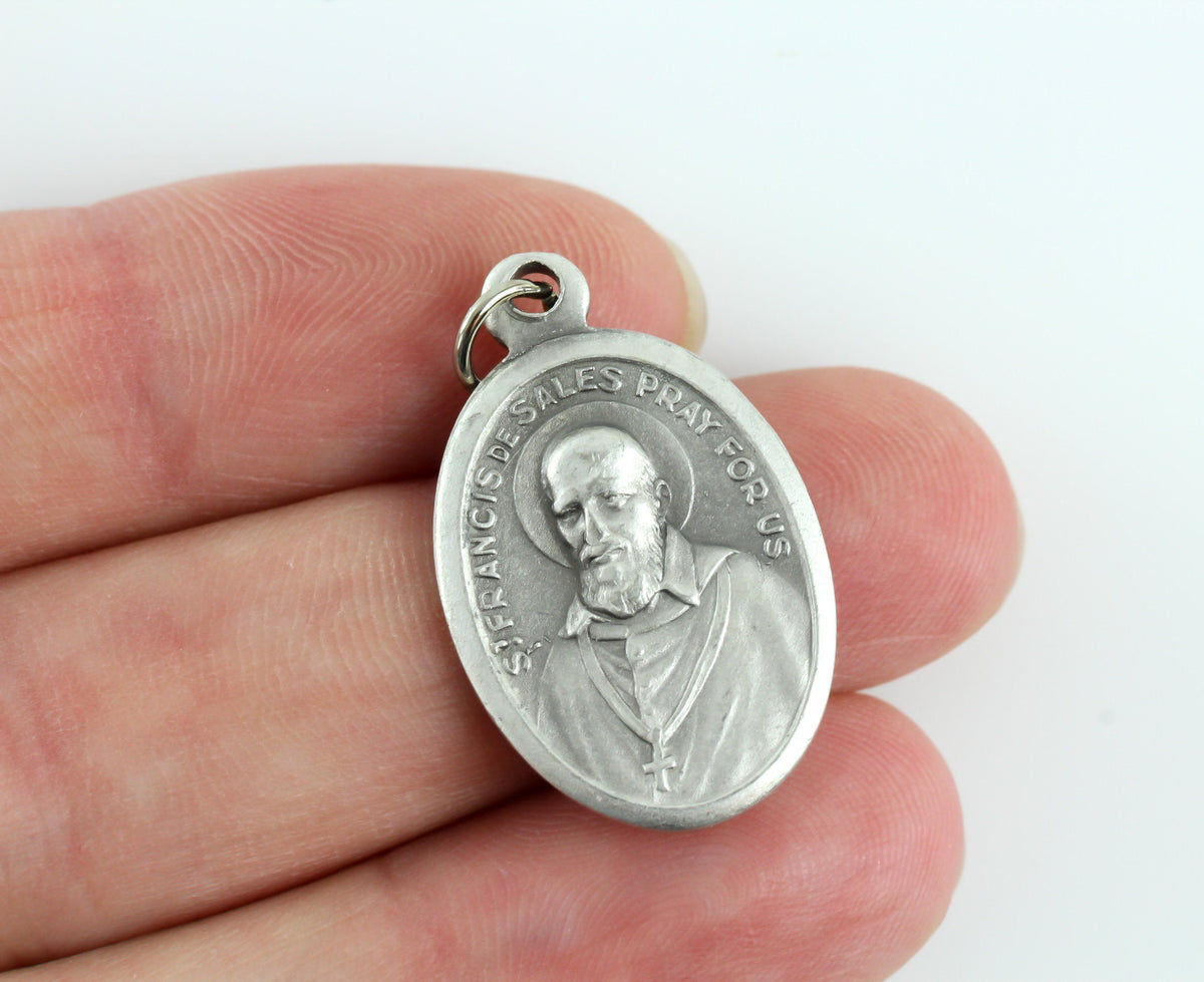 womans hand holding die cast patron saint medal