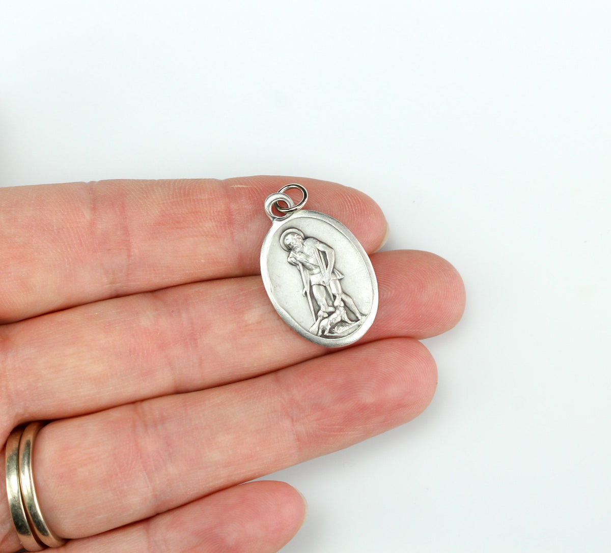 womans hand holding catholic patron saint lazarus medal