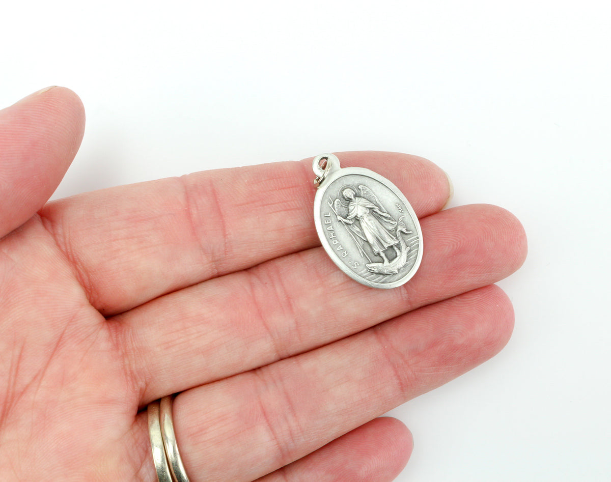 womans hand holding catholic patron saint raphael  medal