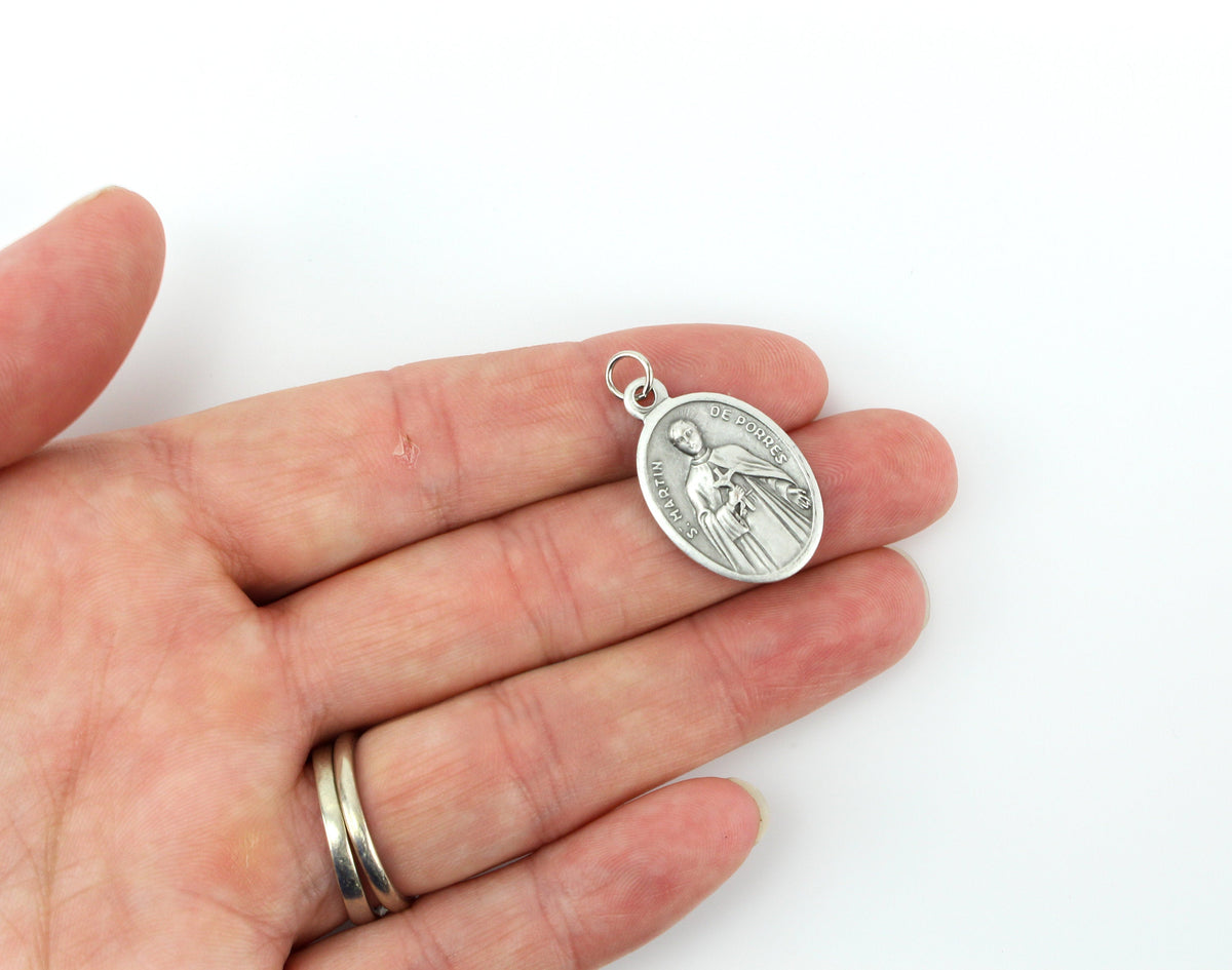 womans hand holding catholic patron saint medal