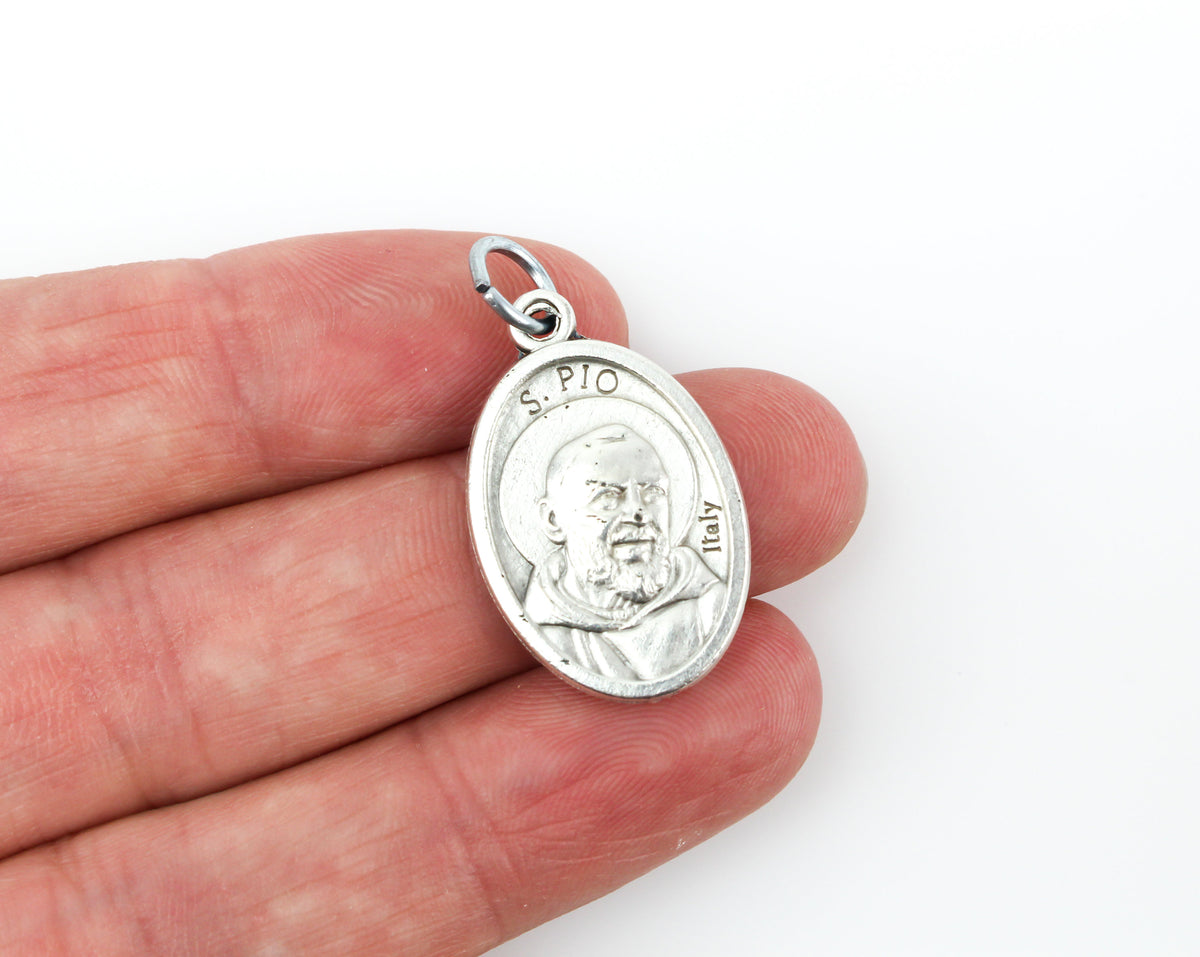 womans hand holding catholic patron saint padre pio medal