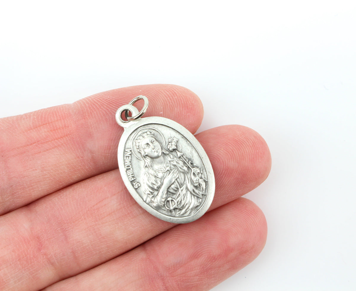 womans hand holding catholic patron saint philomena medal
