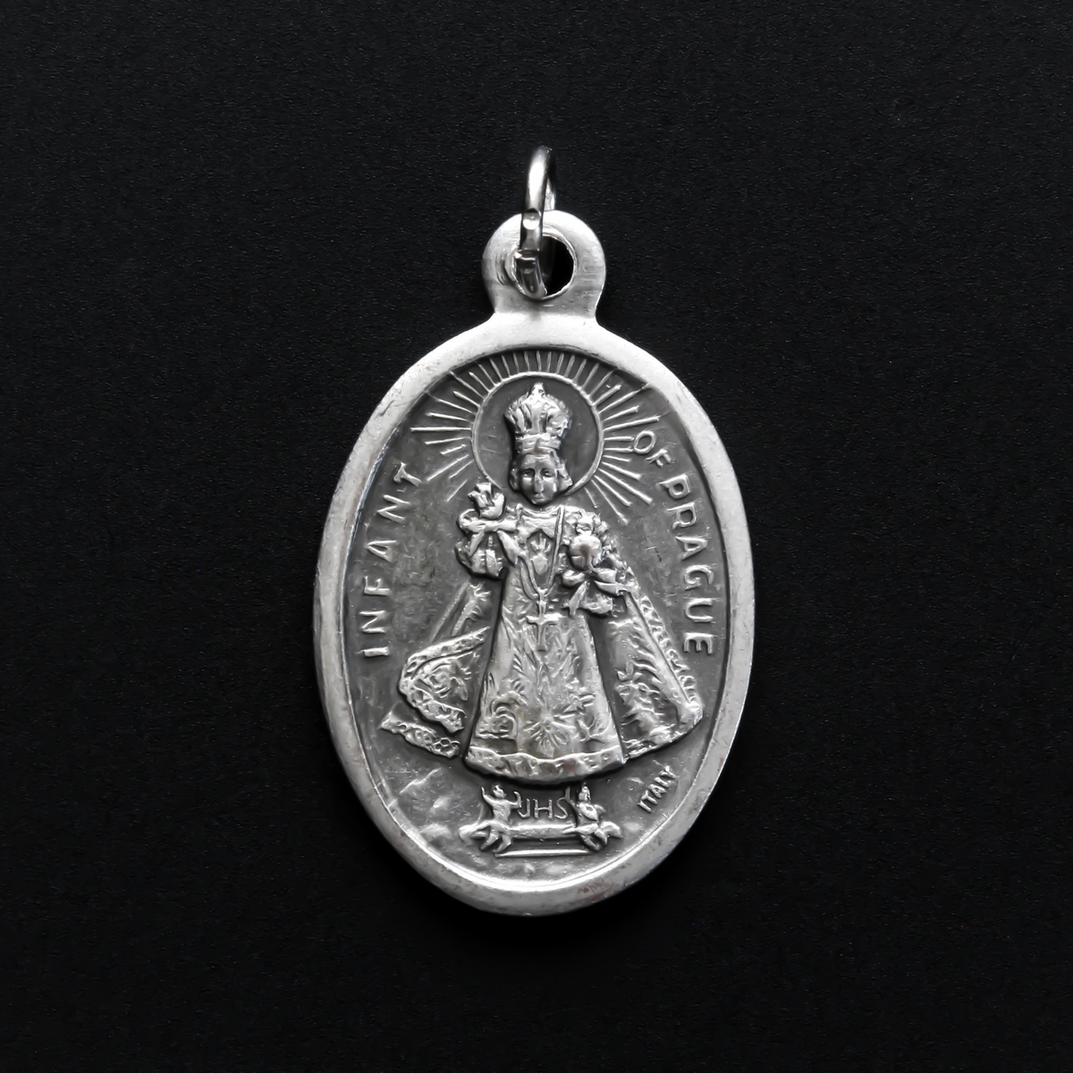 Infant Jesus of Prague medal that depicts the Infant Jesus on the front and is marked "Pray For Us" on the back