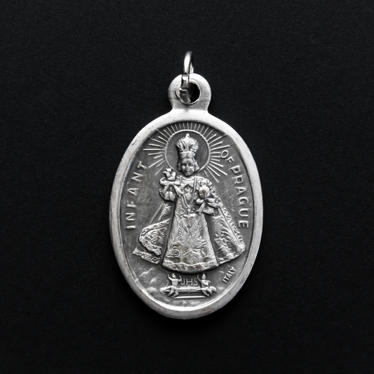 Infant Jesus of Prague medal that depicts the Infant Jesus on the front and is marked "Pray For Us" on the back