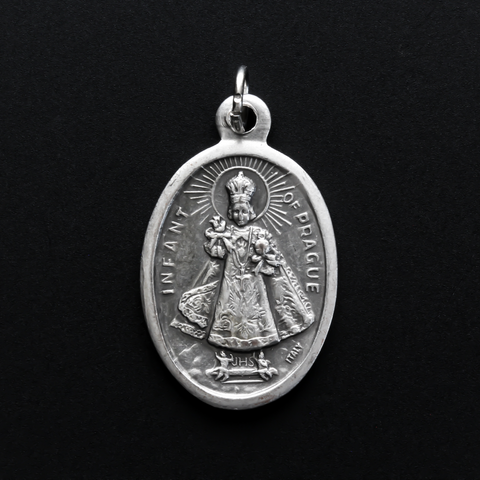 Infant Jesus of Prague medal that depicts the Infant Jesus on the front and is marked "Pray For Us" on the back