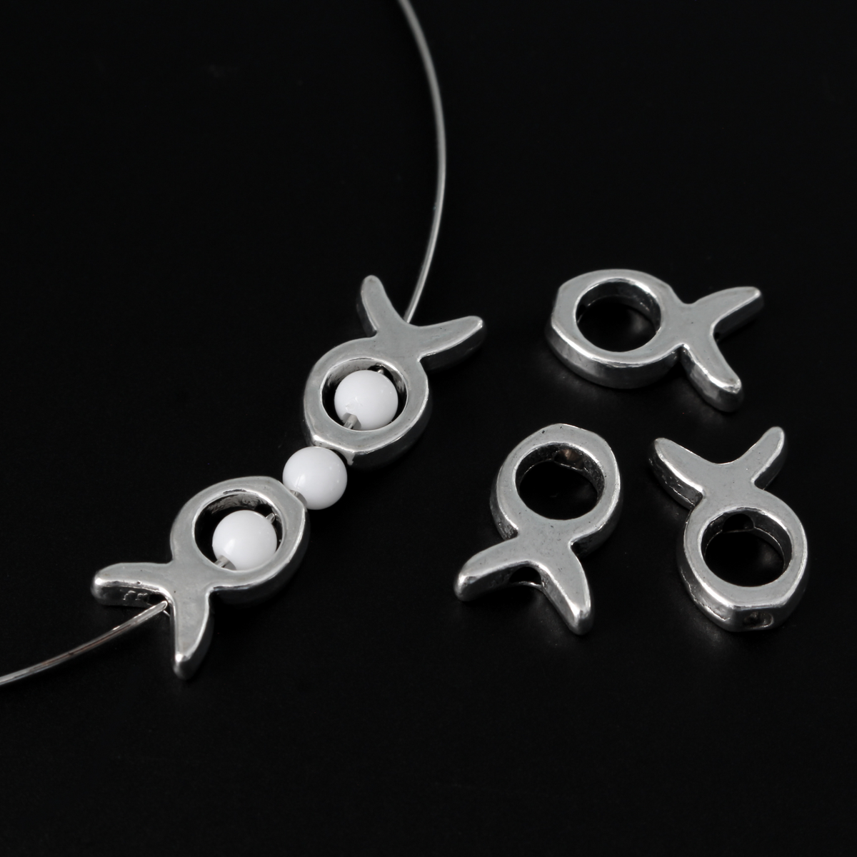 Silver tone bead frames that are shaped like a fish. They fit beads 4mm or smaller 