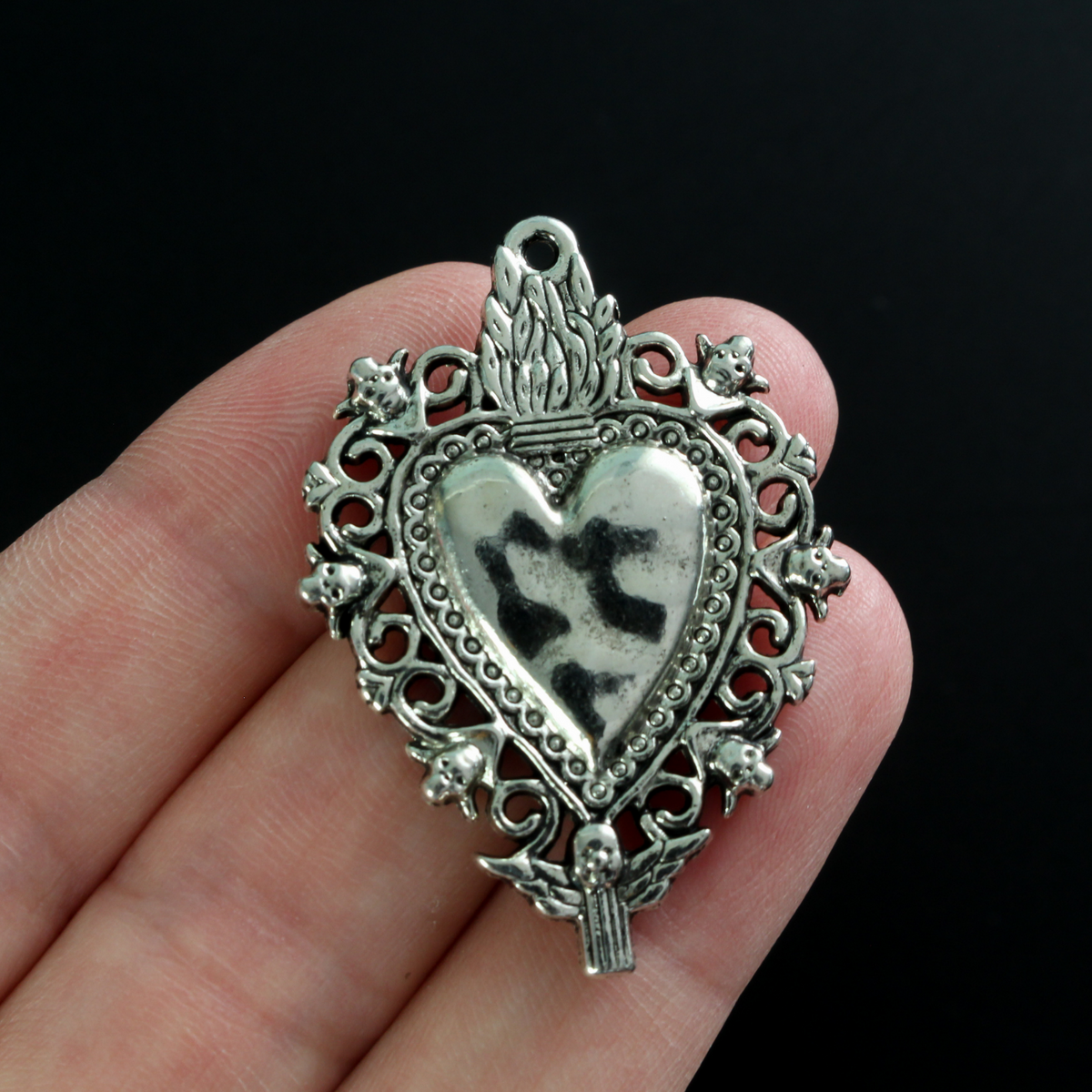 Unique Sacred Heart Milagro style pendant with skulls around the border a winged angel at the bottom.