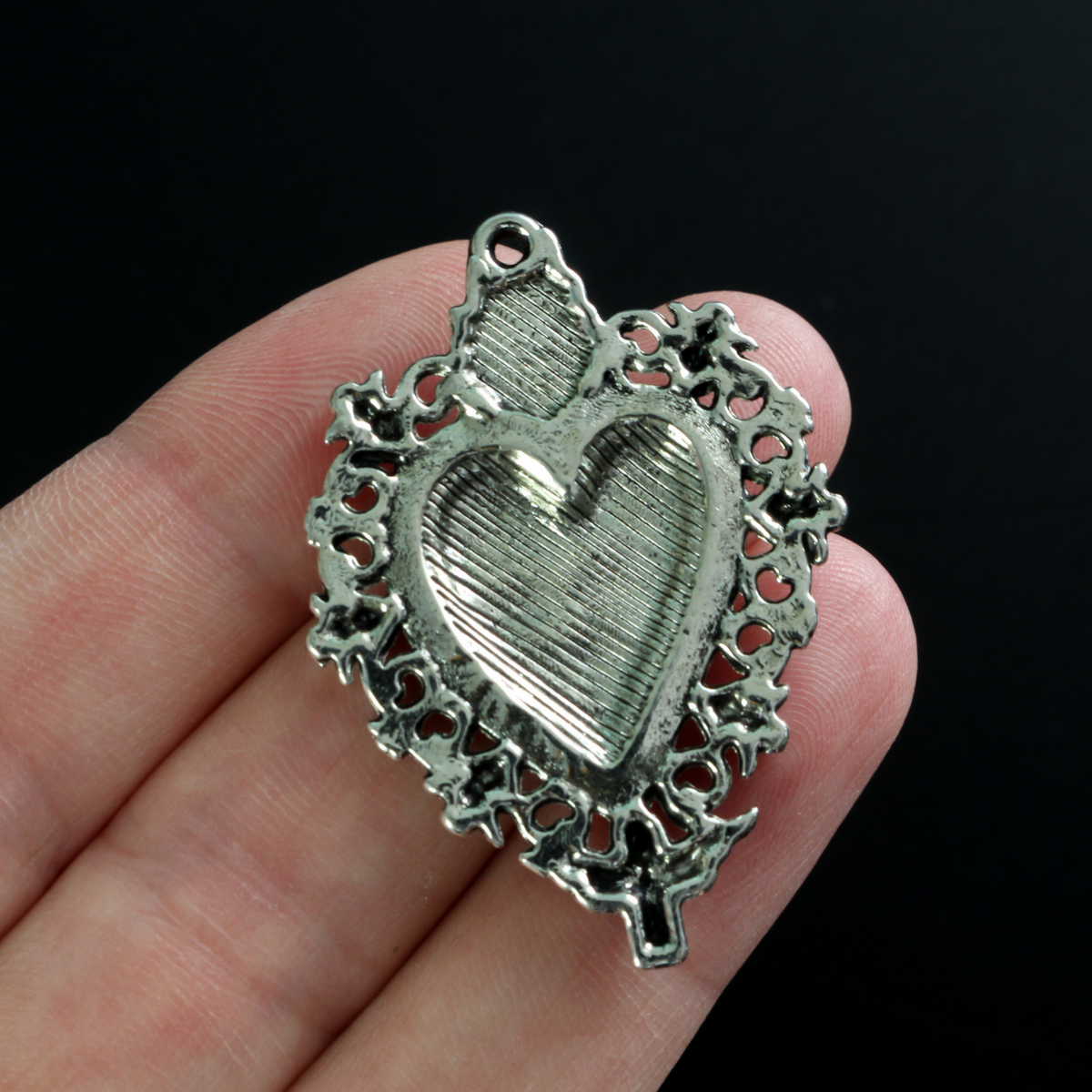 Unique Sacred Heart Milagro style pendant with skulls around the border a winged angel at the bottom.