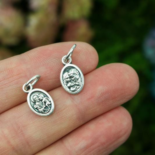 1/2" long medal that depicts Saint Joseph holding the child Jesus on one side and the Holy Family depicted on the other side