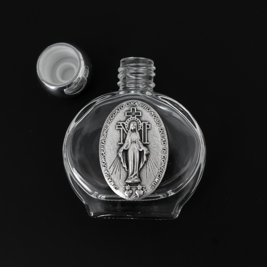 Glass holy water bottle with a metal embossed plaque of The Miraculous Medal on the front. Plastic screw on cap that is a shiny silver tone color.