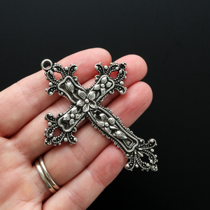 Large ornate cross pendant that has lilies on the crossbars and ornate fleur de lis on the ends 73mm long