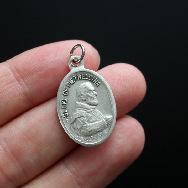 Saint Pio Padre oval medal that depicts the saint on the front and "Pray For Us