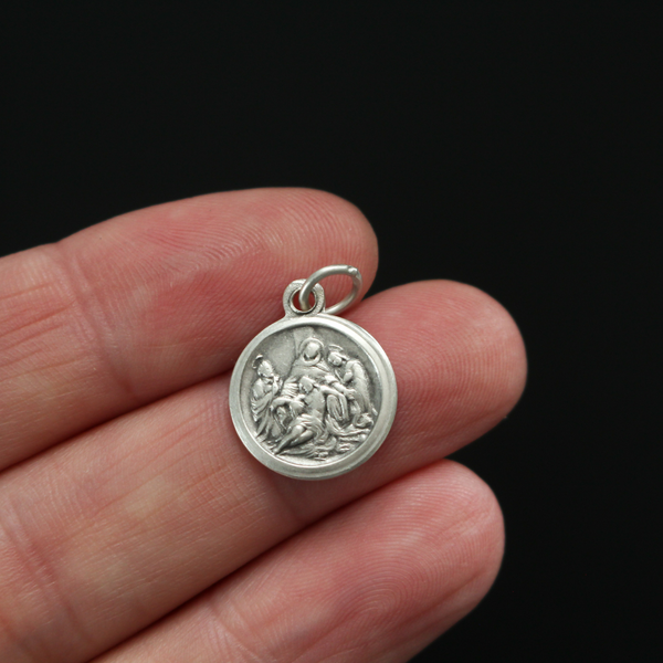 Small round Pieta medal that depicts the thirteen station of the Via Dolorosa when Jesus is taken down from the Cross and given to his Mother