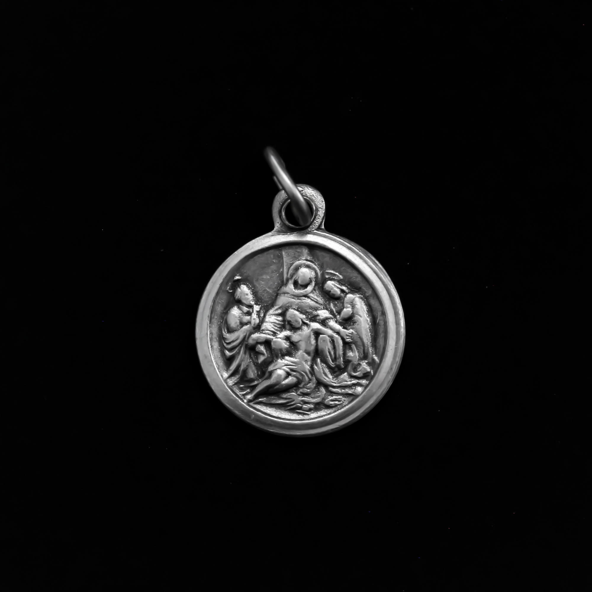 Small round Pieta medal that depicts the thirteen station of the Via Dolorosa when Jesus is taken down from the Cross and given to his Mother