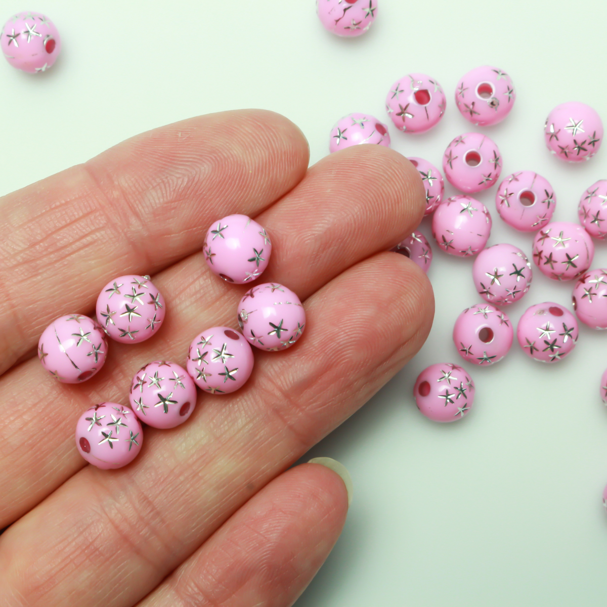 8mm Round pink opaque beads that have a silver star design etched into them. 