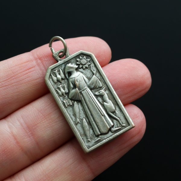 Unique rectangle-shaped pendant depicting Saint Francis surrounded by animals. Marked "Pray For Us" on the back