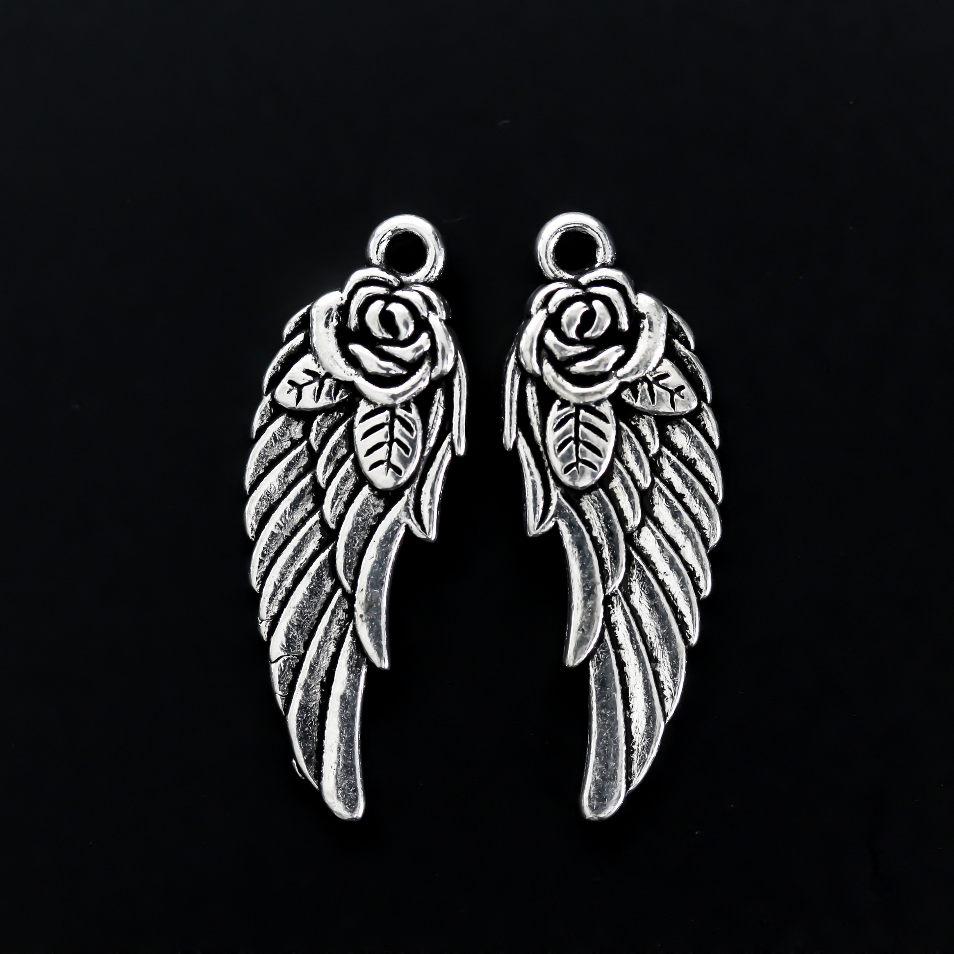 Double-sided wing charm with a rose detail at the top. The charm looks the same on both sides, 32mm long