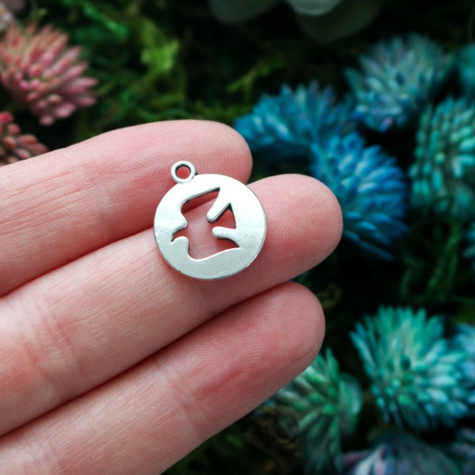 Round silver-tone charm with a cut-out dove in the center.