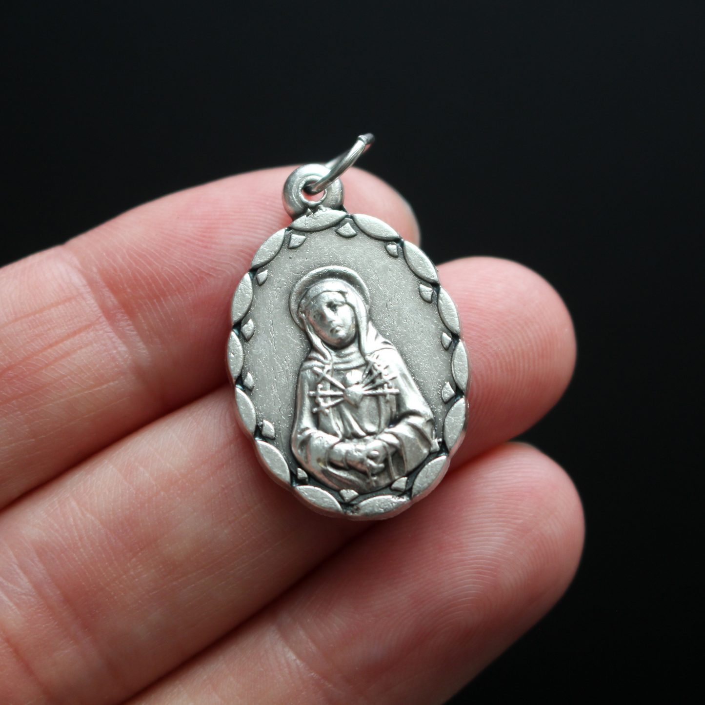 Our Lady of the Seven Sorrows medal that depicts the Virgin Mary on the front, her heart is pierced by seven swords which represent the seven sorrows.