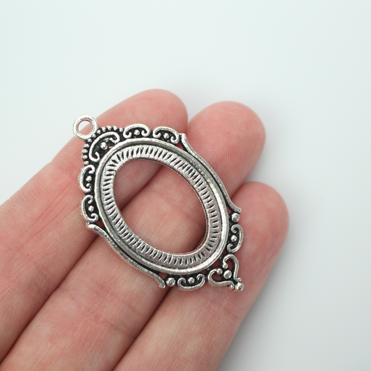 Ornate oval antiqued silver style cabochon setting with an open back