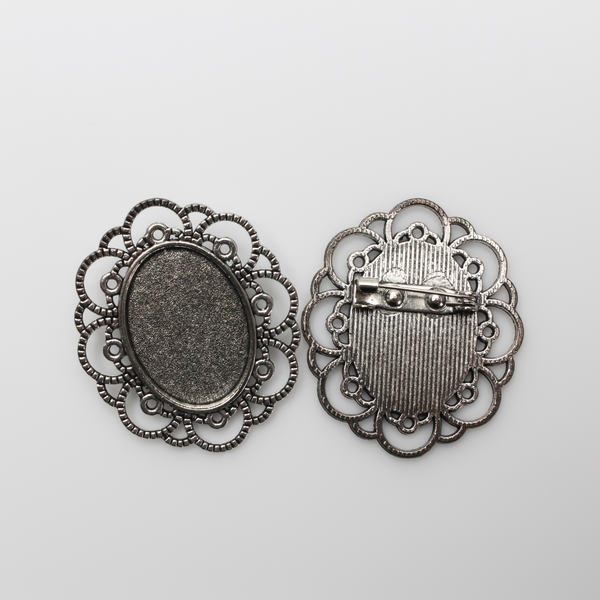Silver tone oval bezel brooch pin with an ornate filigree border. The tray size on this bezel is 25mm x 18mm