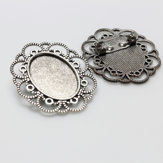 Silver tone oval bezel brooch pin with an ornate filigree border. The tray size on this bezel is 25mm x 18mm