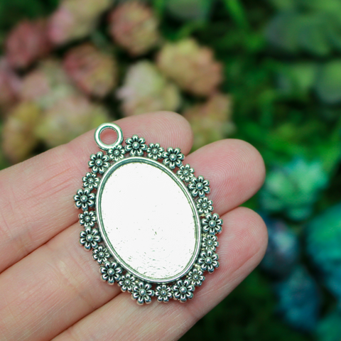 Silver ornate oval bezel tray setting with an ornate flower embellished trim.