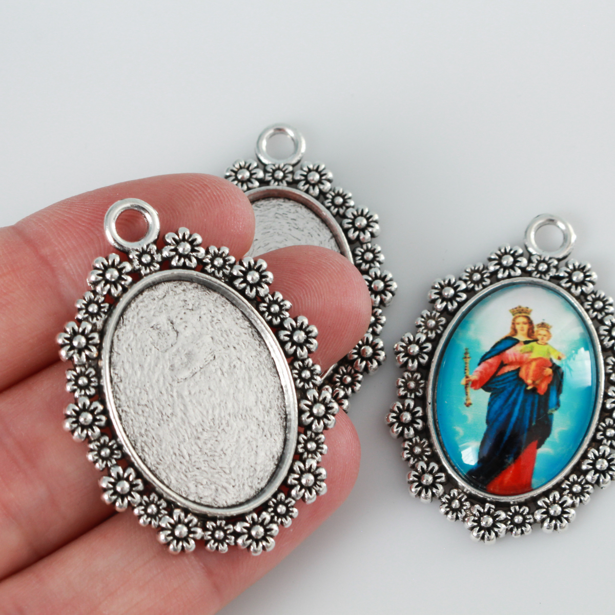 Silver ornate oval bezel tray setting with an ornate flower embellished trim.