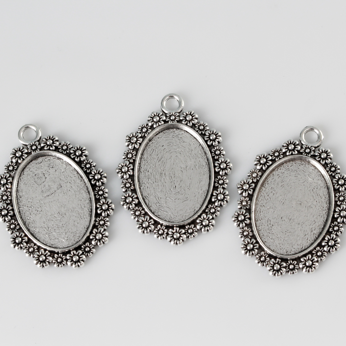 Silver ornate oval bezel tray setting with an ornate flower embellished trim.