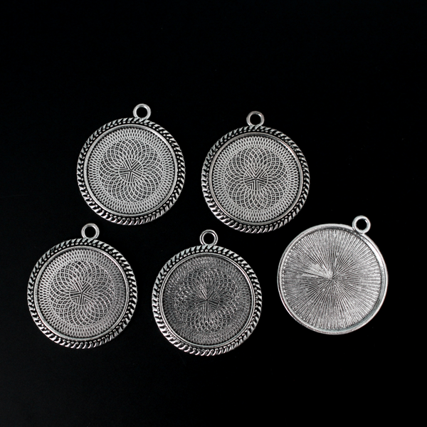 Round pendant cabochon setting in an antiqued silver color. There is a pattern along the edge of the cup. The tray fits 25mm cabochons