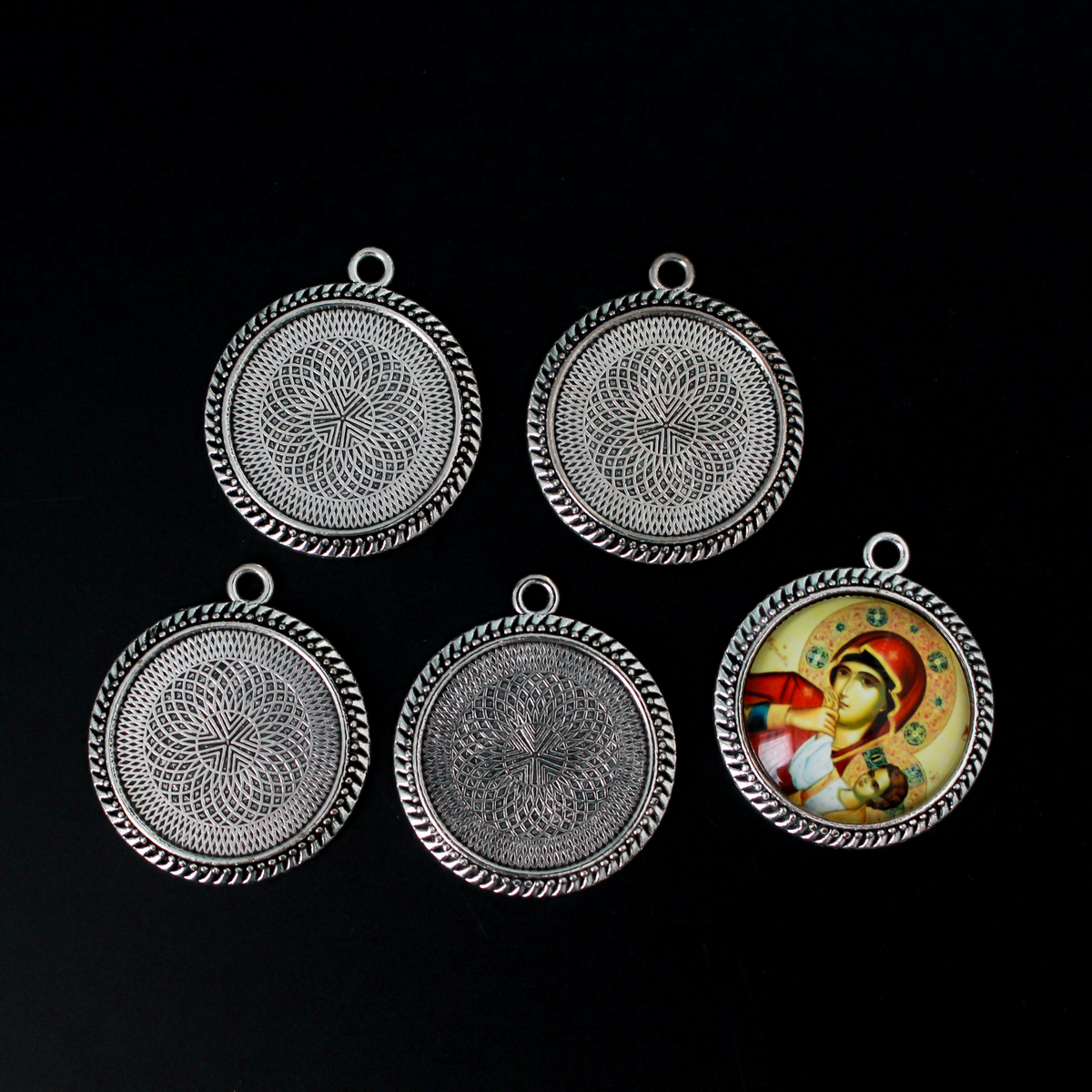 Round pendant cabochon setting in an antiqued silver color. There is a pattern along the edge of the cup. The tray fits 25mm cabochons
