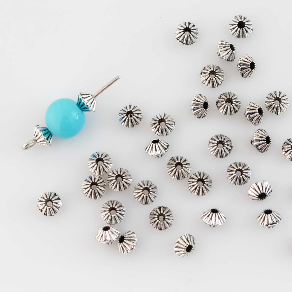 100 metal bicone shaped spacer beads with an antiqued silver finish and a corrugated pattern