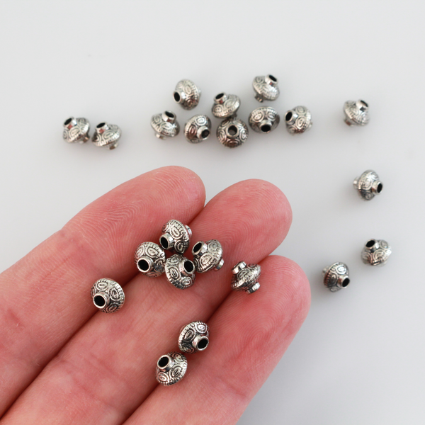 50 metal bicone shaped spacer beads with an antiqued silver finish and a carved dot pattern
