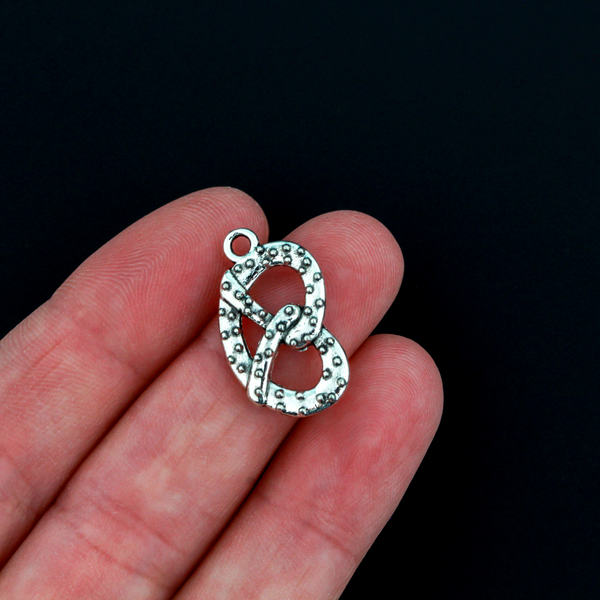 Small silver tone pretzel charm, sold in sets of three. This is a double-sided charm and looks the same on both sides.