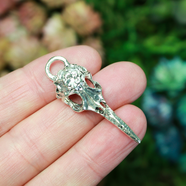 Antiqued silver tone raven skull charms that have a flower design on the top