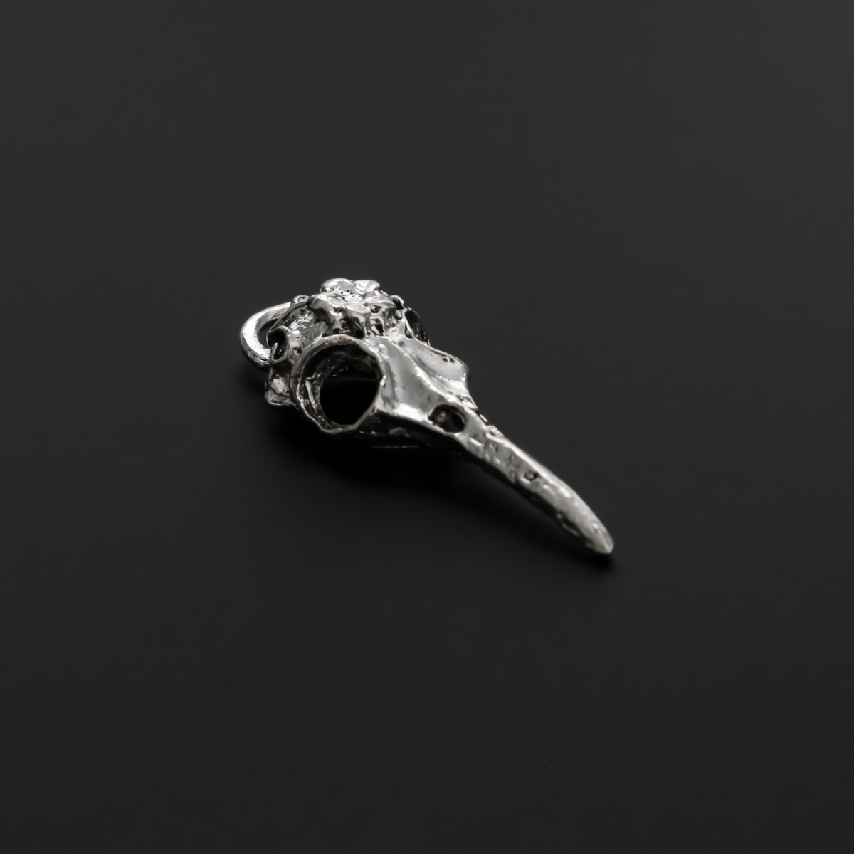 Antiqued silver tone raven skull charms that have a flower design on the top