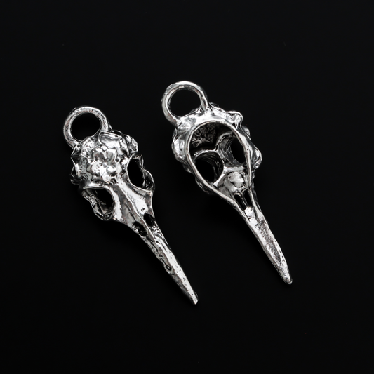 Antiqued silver tone raven skull charms that have a flower design on the top