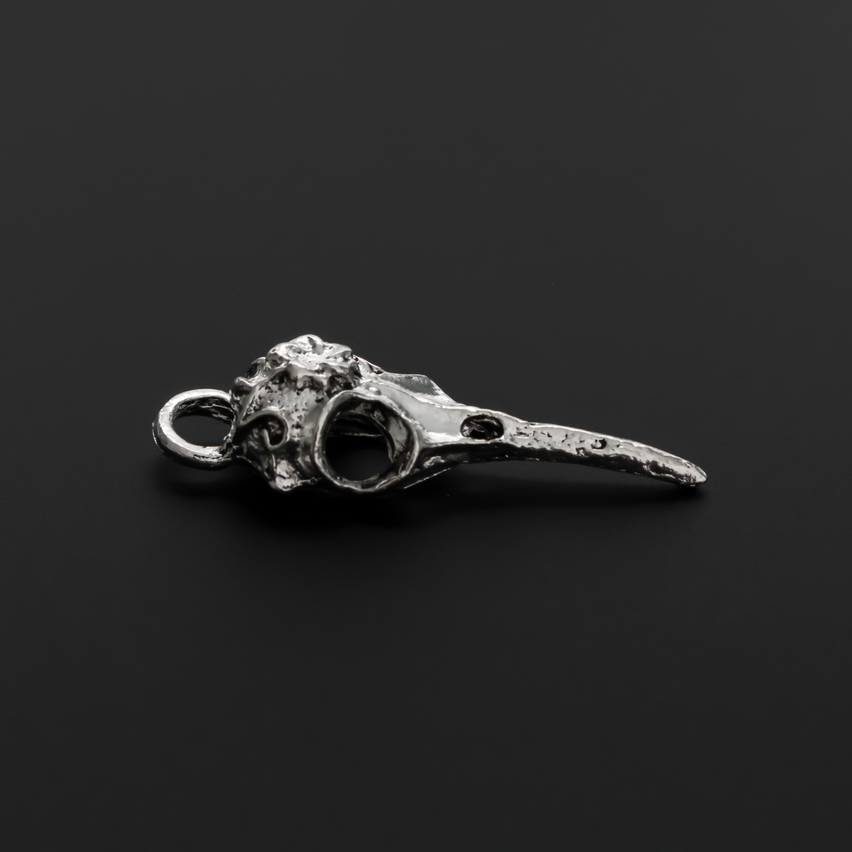 Antiqued silver tone raven skull charms that have a flower design on the top