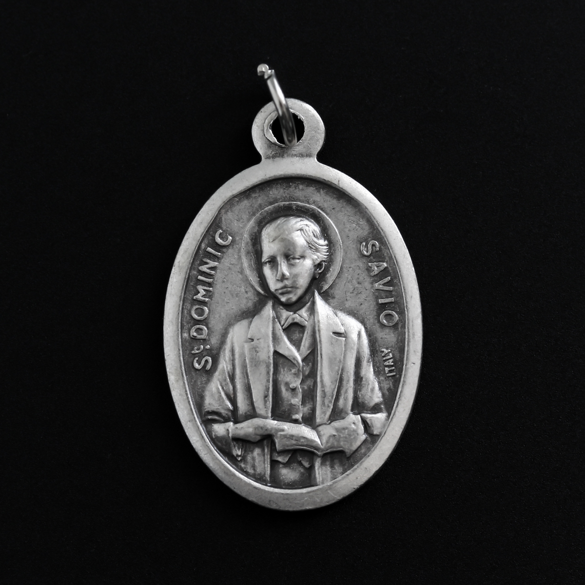 Saint Dominic Savio medal that depicts the saint on the front and "Pray For Us" on the back