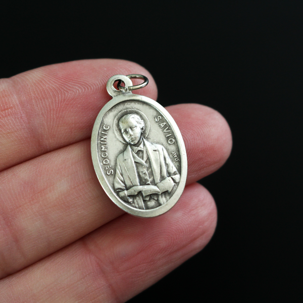 Saint Dominic Savio medal that depicts the saint on the front and "Pray For Us" on the back