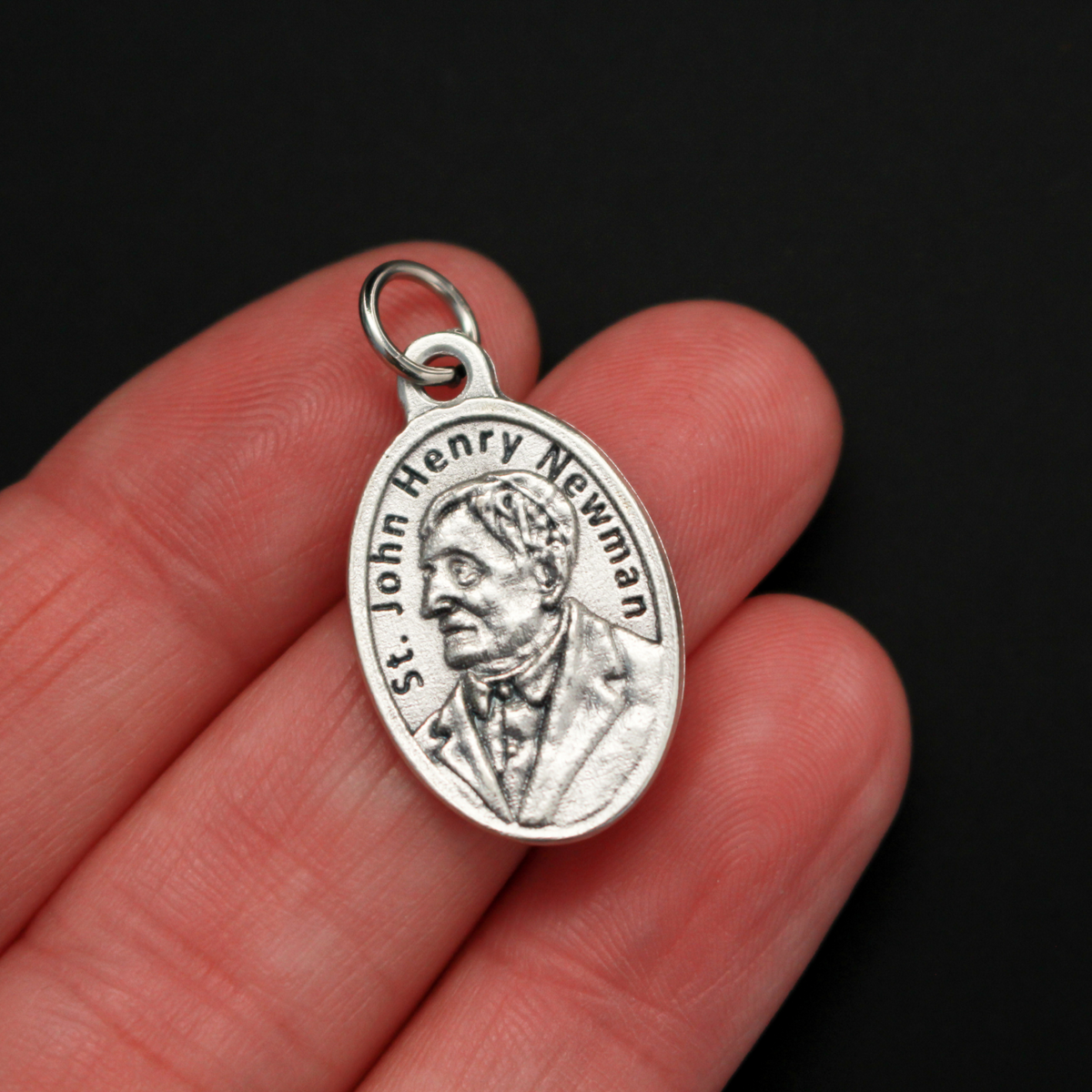 Saint John Henry Newman medal that depicts the saint on the front and is marked "Pray For Us" on the back
