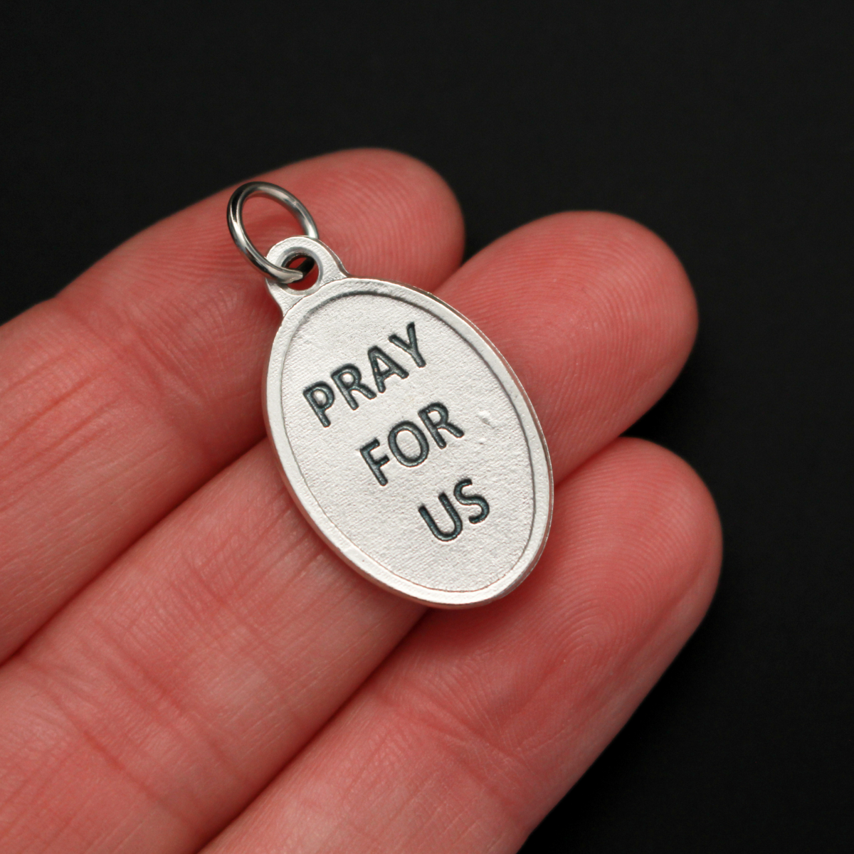 Saint John Henry Newman medal that depicts the saint on the front and is marked "Pray For Us" on the back